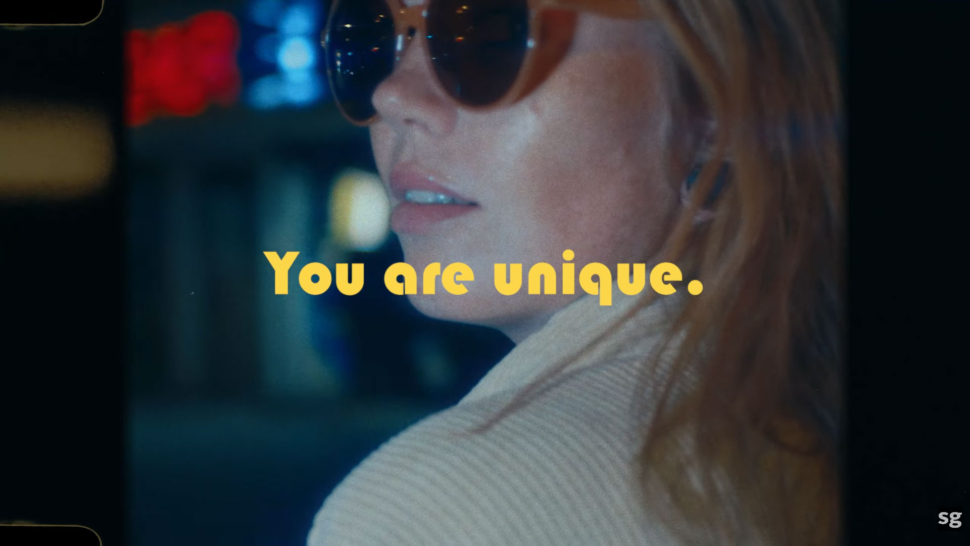 A young woman in sunglasses at night with "You Are Unique" text overlay, showcasing video editing for brand storytelling.