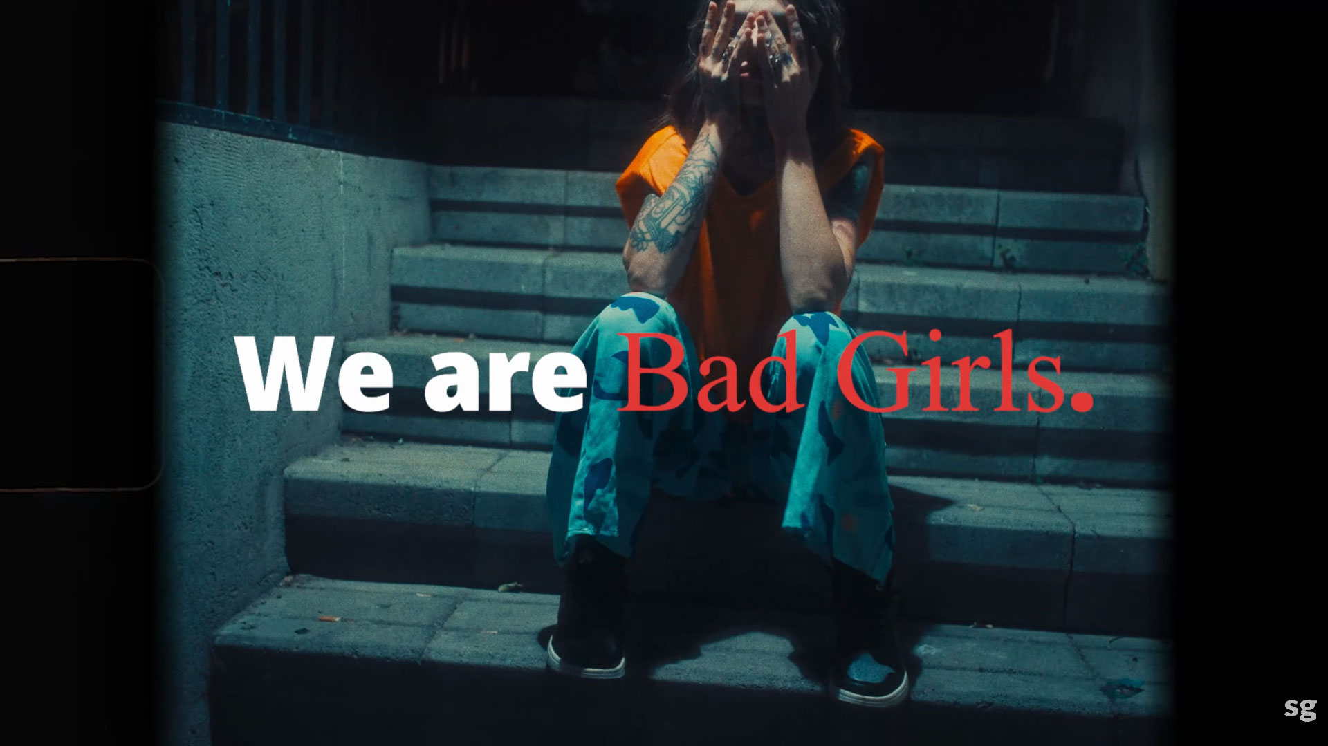 A woman in orange clothing sitting on steps with "We Are Bad Girls" text, highlighting high-impact video editing for brand storytelling.