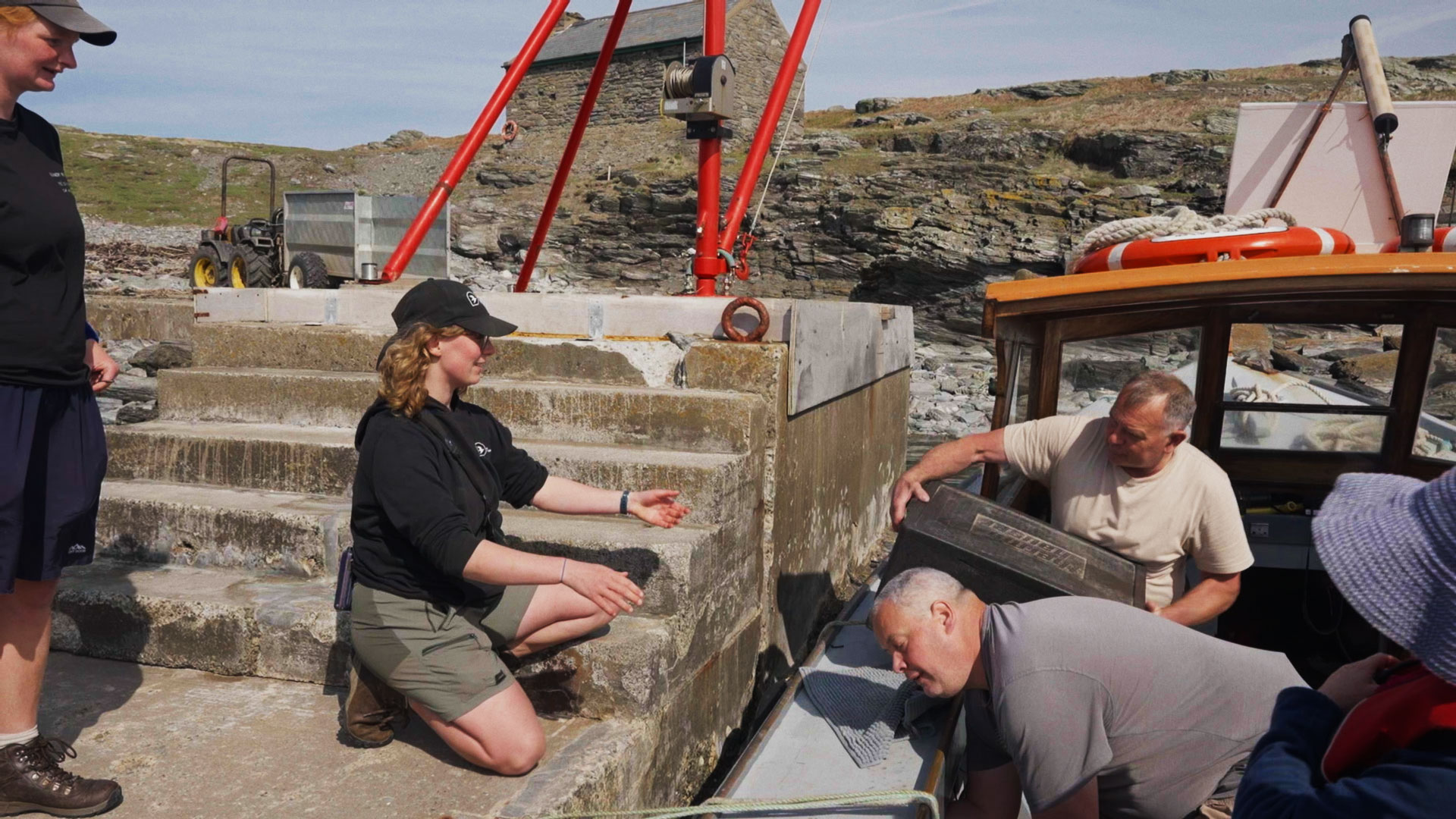 A scene showing the logistics of remote island conservation, featuring wardens unloading essential supplies on the Calf of Man.